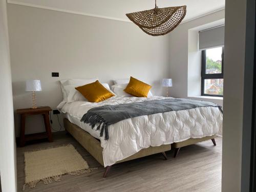 1 dormitorio blanco con 1 cama grande con almohadas amarillas en The Roses, en Puerto Varas