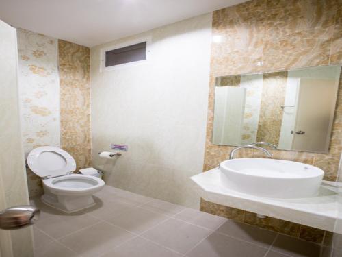 a bathroom with a toilet and a sink and a mirror at P.A. Thani Hotel in Nakhon Sawan