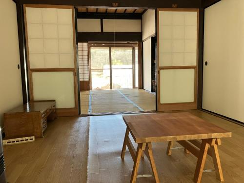 una habitación con una mesa de madera y una habitación con puertas en 古民家HAKKOU kibi 