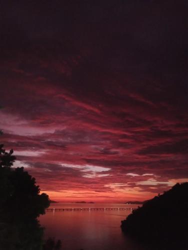 een rode zonsondergang boven een lichaam van water bij Casa do Maycon in Mangaratiba