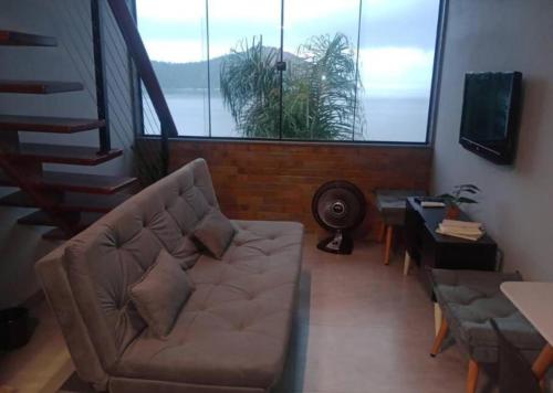 een woonkamer met een bank en een groot raam bij Casa do Maycon in Mangaratiba