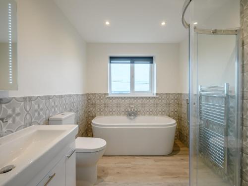 a bathroom with a tub and a toilet and a sink at 3 Bed in Worth Matravers 80578 in Worth Matravers