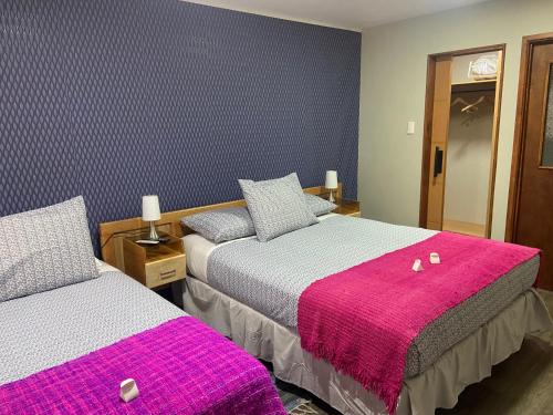 a bedroom with two beds with pink blankets at Cabañas Bosque Austral in Punta Arenas