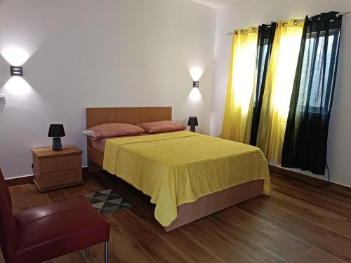 a bedroom with a bed with a yellow bedspread at Espaço-Vila Verde 