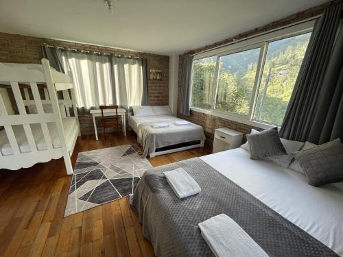 a bedroom with two beds and a large window at RIVERSIDE RESINDENCE con Jacuzzy in Baños