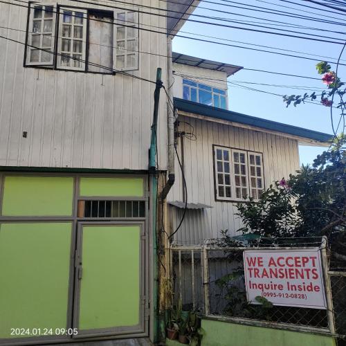 a sign in front of a house with a building at Kochimoto Bed & Bath in Baguio