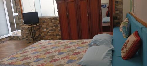 a bedroom with a blue bed and a tv at SUITE CONFORTABLE CAROLINA in Quito