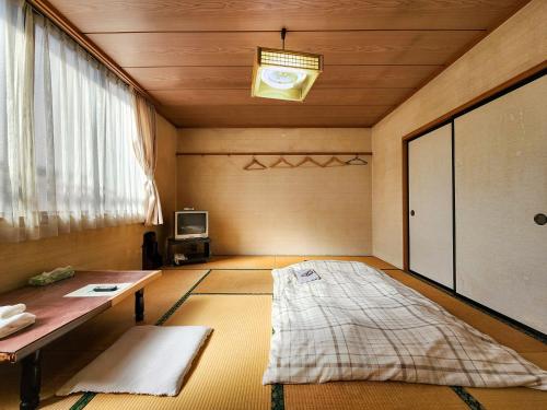 a room with a bed and a table and a window at Yukikan in Yuki