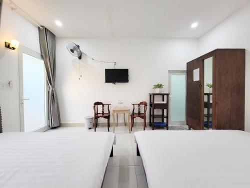a room with two beds and a table with chairs at Amy Motel Xuyên Mộc in Xuyên Mộc
