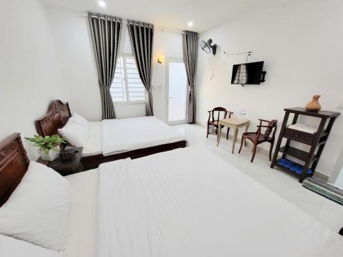 a living room with two beds and a table and chairs at Amy Motel Xuyên Mộc in Xuyên Mộc