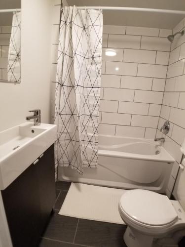La salle de bains est pourvue de toilettes, d'un lavabo et d'une douche. dans l'établissement Modern and spacious 2 bedroom in Montreal, à Montréal