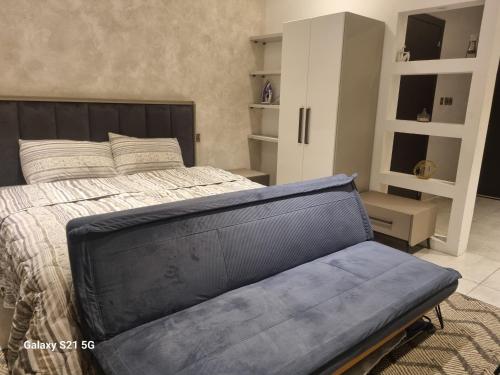 ein Schlafzimmer mit einem Bett und einem blauen Ledersofa in der Unterkunft M.R APARTMENTS in Accra