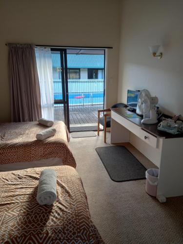 Habitación con 2 camas y escritorio con ventana. en Pinelodge en Opua
