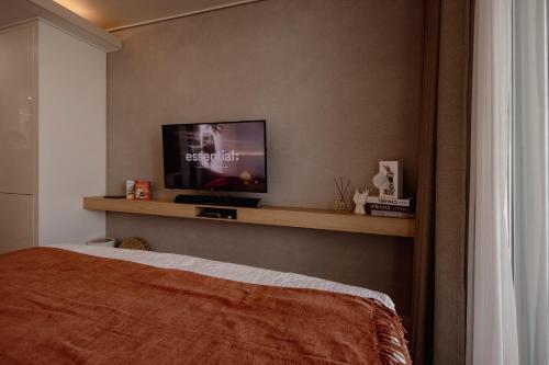 ein Schlafzimmer mit einem Bett und einem Fernseher auf einem Regal in der Unterkunft 영종도 구읍뱃터 오션뷰-Luxe 베드,넷플릭스, 사운드바, 식물테리어, 무료주차 in Incheon