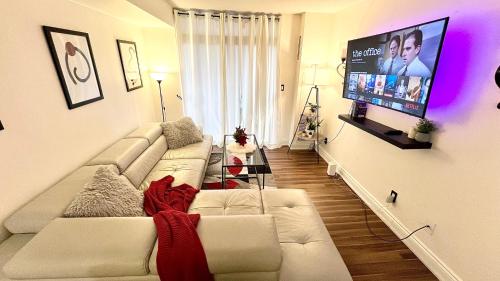 a living room with a white couch and a flat screen tv at Modern & Cozy 1BR w/ parking by Square One in Mississauga