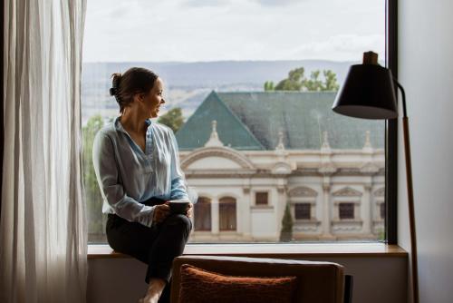 a woman sitting on a window sill looking out at Hotel Verge Launceston in Launceston