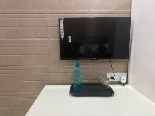 a bottle on a black tray on a table with a television at As Hotel Expo Inn in Greater Noida