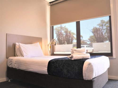 a bedroom with a large bed with a window at Eastend Studio Apartments in Dubbo