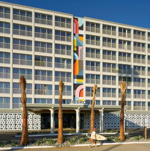a woman walking in front of a hotel with a surfboard at Viceroy Santa Monica in Los Angeles