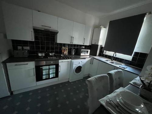a kitchen with white cabinets and a washing machine at Centrally located stylish family suit Next to the train station in London
