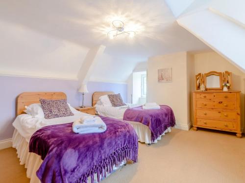 a bedroom with two beds with purple comforters at 2 Bed in Rothbury 74811 in Rothbury