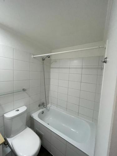 a white bathroom with a toilet and a bath tub at Departamento Cómodo en Santiago in Santiago