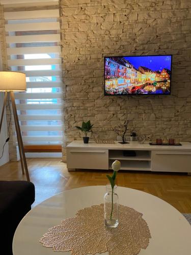sala de estar con TV en una pared de ladrillo en Annabel’s Home, en Sarajevo