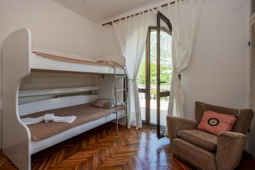 a bedroom with two bunk beds and a chair at Villa D'amore Montenegro in Donji Morinj
