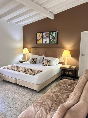 a bedroom with a large bed and two tables and lamps at Hotel Aromax del Campestre in Medellín
