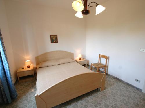 a bedroom with a bed and two tables and a chair at L' Oleandro in Marina di Campo