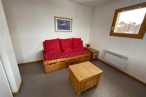 Cette chambre dispose d'un canapé en bois et d'oreillers rouges. dans l'établissement Family cocoon at the foot of the slopes, à Saint-Étienne-en-Dévoluy