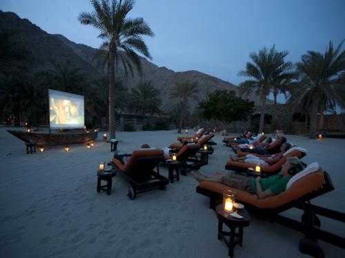 a group of people sitting on lounge chairs on a beach at Six Senses Zighy Bay in Dibba