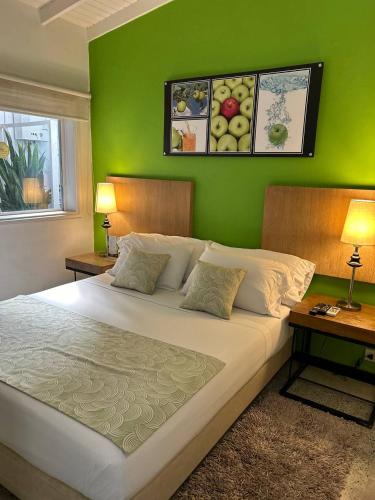 a bedroom with a large bed with a green wall at Hotel Aromax del Campestre in Medellín