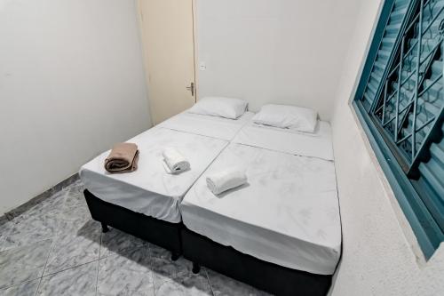 a bedroom with a bed with a bag on it at Quarto 03 Pousada Roosevelt in Uberlândia