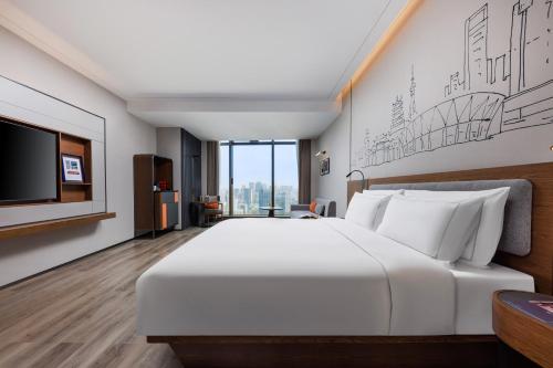 a bedroom with a large white bed and a flat screen tv at UrCove by Hyatt Foshan Downtown in Foshan