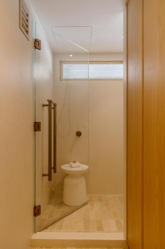 a bathroom with a toilet and a glass shower at Netanya Noosa Beachfront Resort in Noosa Heads