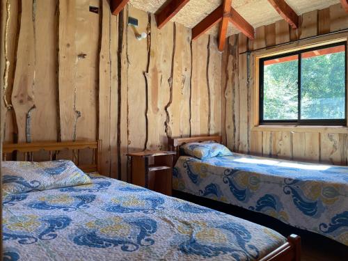 a bedroom with two beds in a wooden cabin at Valle Hermoso in Panguipulli