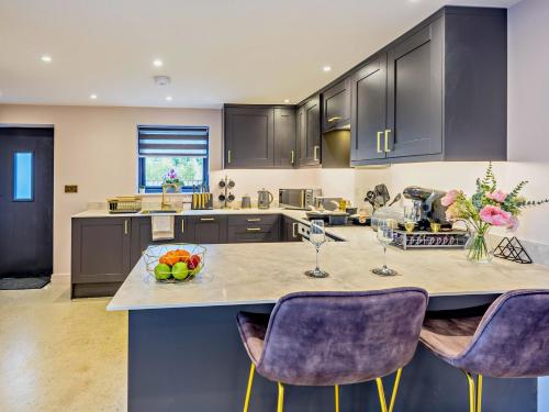 a kitchen with purple chairs and a island with a table at 2 Bed in Barnstaple 91637 in Fremington