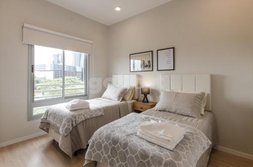 Duas camas num quarto com uma janela em Modern 2 Bedroom Apartment Near Paseo La Galeria em Assunção