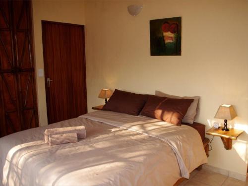 a large bed in a bedroom with two lamps at Les 3 Marulas in Marloth Park