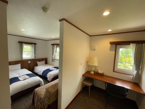Habitación de hotel con 2 camas y escritorio en Kiyosatokogen Country Inn The Classic, en Hokuto