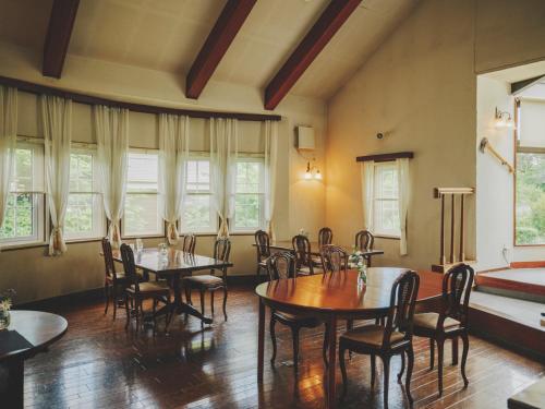 a dining room with tables and chairs and windows at Kiyosatokogen Country Inn The Classic in Hokuto