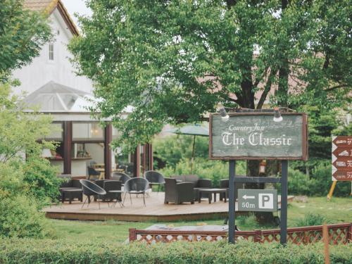 a sign in front of a restaurant with tables and chairs at Kiyosatokogen Country Inn The Classic in Hokuto