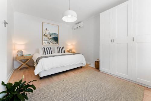 a white bedroom with a white bed and a table at Belle Escapes - Bountiful Family Oasis in West Beach in Henley Beach South