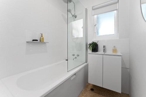 La salle de bains blanche est pourvue d'une douche et d'un lavabo. dans l'établissement Belle Escapes - Bountiful Family Oasis in West Beach, à Henley Beach South