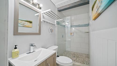 a white bathroom with a sink and a toilet at Jacksonville Beach Home - Walk to Beach, Bars & Restaurants - Pet Friendly in Jacksonville Beach