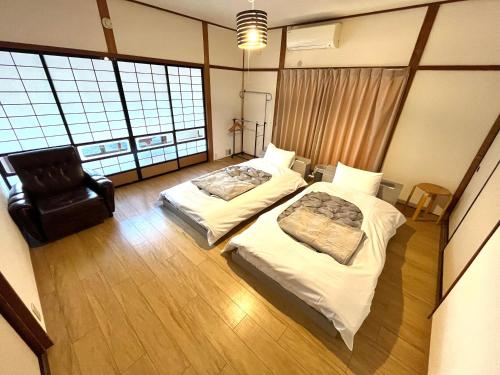 una habitación de hotel con 2 camas y una silla en オオヤシロSTAY旅音 en Izumo