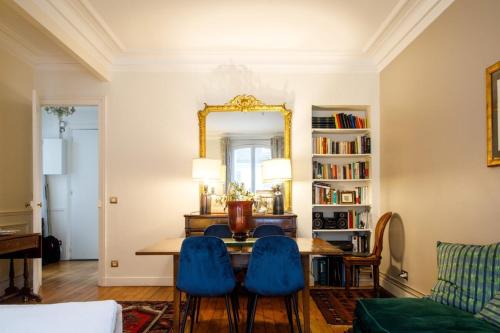 - un salon avec une table, des chaises bleues et un miroir dans l'établissement Stylishly Decorated 2BD Apartment Montmatre!, à Paris