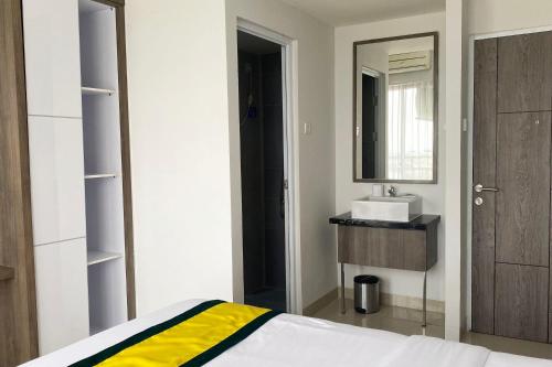 um quarto com uma cama, um lavatório e um espelho em Hotel Dhika Serenity Surabaya em Surabaya