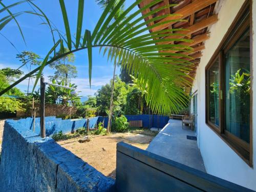 ein Haus mit einer Palme neben einem Zaun in der Unterkunft Bangalô com Vista Parcial para o Mar in São Sebastião